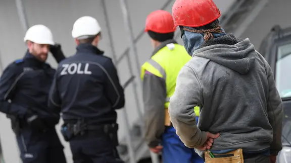 Beamte des Zoll kontrollieren Bauarbeiter während eines Einsatzes auf einer Großbaustelle im Stadtteil Niederrad