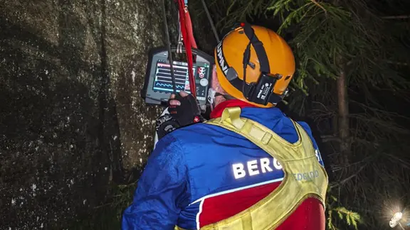 Ein Mitarbeiter der Bergwacht hängt im Dunkeln an einer Felswand
