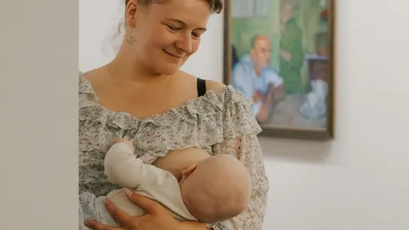 Foto aus der Kampagne Ich still wo ich will: Stillende Frau mit Baby vor Kunstwerk