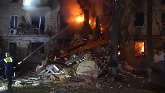 Ein Wohnhaus in der ukrainischen Großstadt Charkiw ist von einem russischen Luftangriff getroffen worden und brennt. Die Feuerwehr löscht das Feuer.