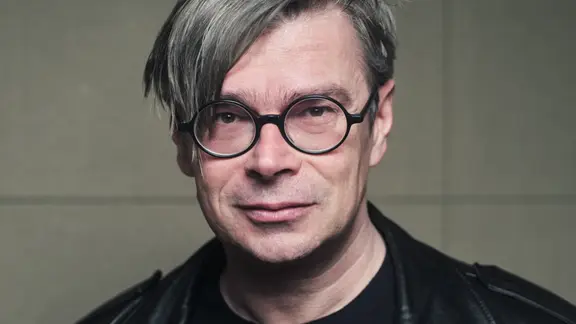 Der Autor Jaroslav Rudiš in schwarzer Lederjacke, mit grauen Haaren und Brille.