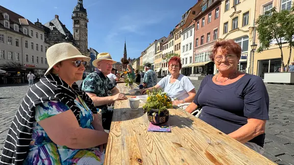 Menschen sitzen an einer langen Tafel auf dem Marktplatz in Altenburg