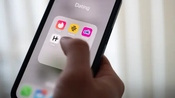 Eine Frau hält ein Smartphone, auf dem Dating-Apps angezeigt werden.