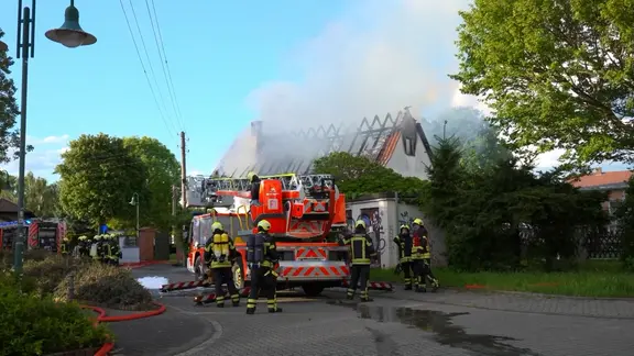 Feuerwehrleute stehen vor einer Brandruine