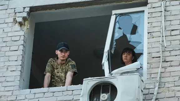 Archivbild: Bewohner blicken aus einem zerstörten Fenster, nachdem ein Wohnhaus bei einem Luftangriff von einer russischen Rakete getroffen wurde.