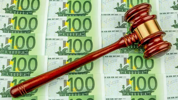 Ein Gerichtshammer liegt auf vielen 100-Euro-Scheinen (Symbolbild).