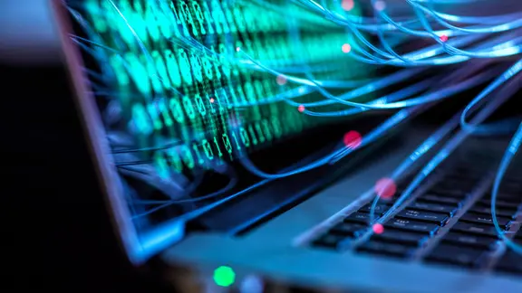 Computervirus und Cyberangriff auf dem Laptop mit Binärcode visualisiert.