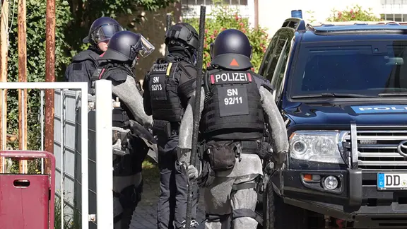 Polizisten einer Sondereinheit der sächsischen Polizei sind mit Helmen, Kettenschutzanzügen und Schutzwesten bereit für einen Einsatz in Freital am 15.8.2026.