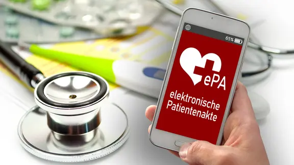 Ein Smartphone wird neben einem Stethoskop in der Hand gehalten.