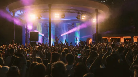 KOSMOS-Festival in Chemnitz. Viele Festivalgäste stehen vor einer beleuchteten Bühne.