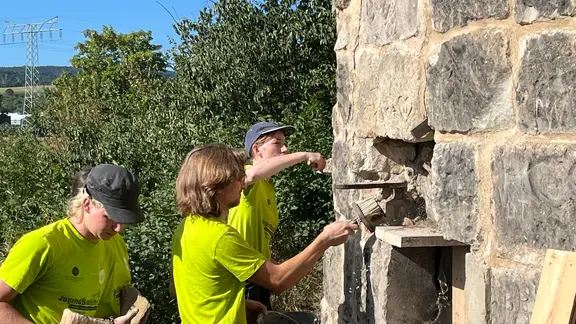 Jugendliche arbeiten an einem alten Wachtturm
