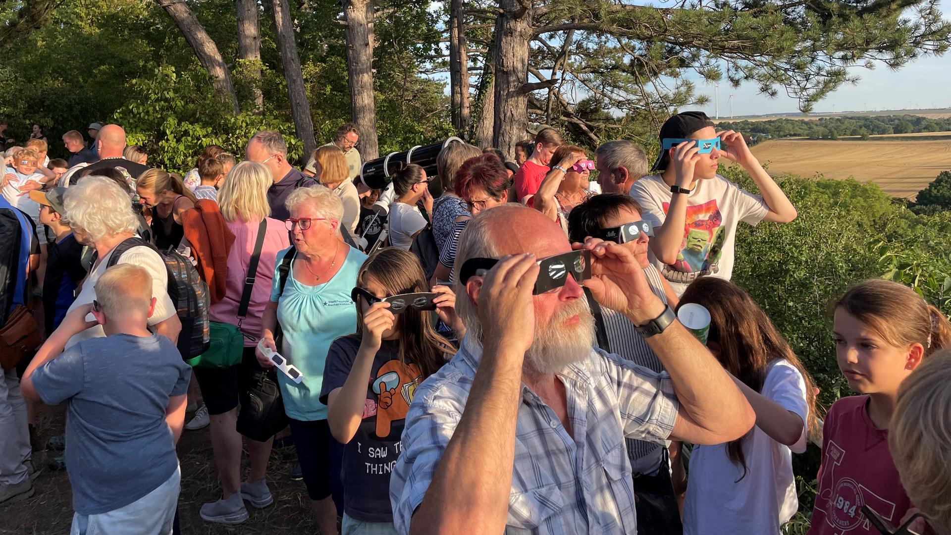 Mehrere Menschen mit Sofi-Brille beobachten eine Sonnenfinsternis. | Swen Wudtke