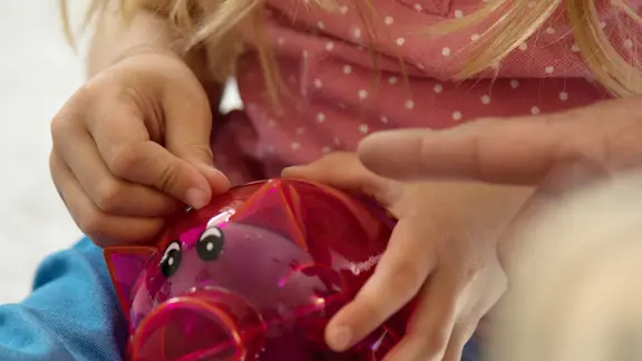 Ein Kind hat ein Sparschwein in der Hand.