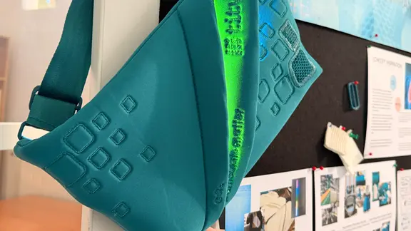 Eine grüne Tasche hängt an einer Stellwand.