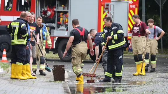 Einsatzkräfte der Feuerwehr reinigen eine zuvor durch Unwetter überflutete Straße.