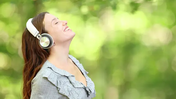 Glückliche Frau atmet und hört Audio im Wald