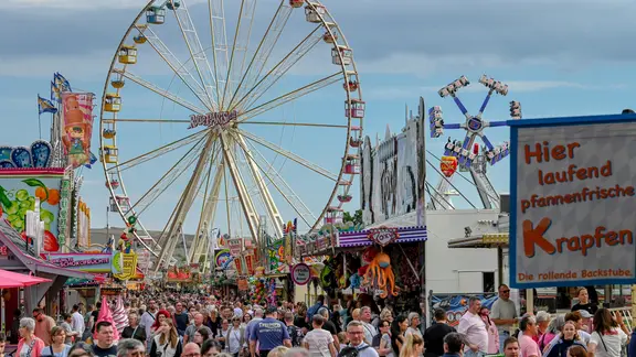 Besucherinnen und Besucher sowie das Riesenrad auf der Eisleber Wiese.