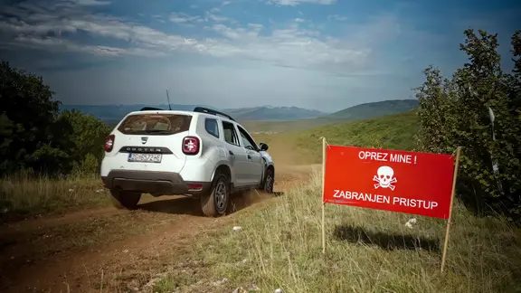 Auto auf Feldweg am Rande einer Minensperrzone im Gebirge