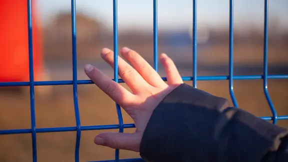 Oblast Moskau: Die Hand eines Mädchens berührt einen Zaun