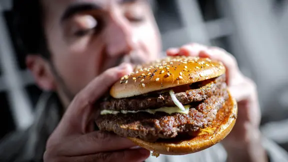 Nahaufnahme eines Burgers, in den ein Mann beißt