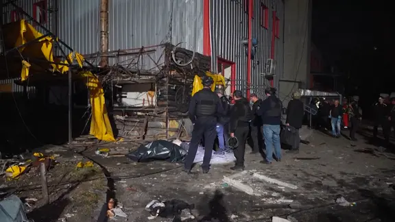 Nach einem russischen Luftangriff auf die ukrainische Stadt Charkiw stehen Einsatzkräfte vor einem Gebäude.
