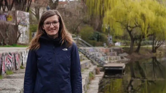 Eine junge Frau mit Brille lächelt in die Kamera.