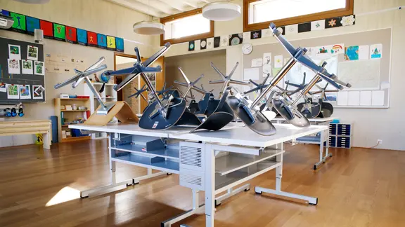 In einem Klassenzimmer sind die Stühle hochgestellt. 