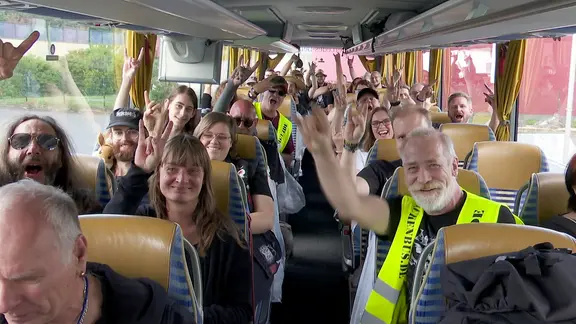 Wacken-Fans zeigen Wacken-Gruss in einem Reisebus