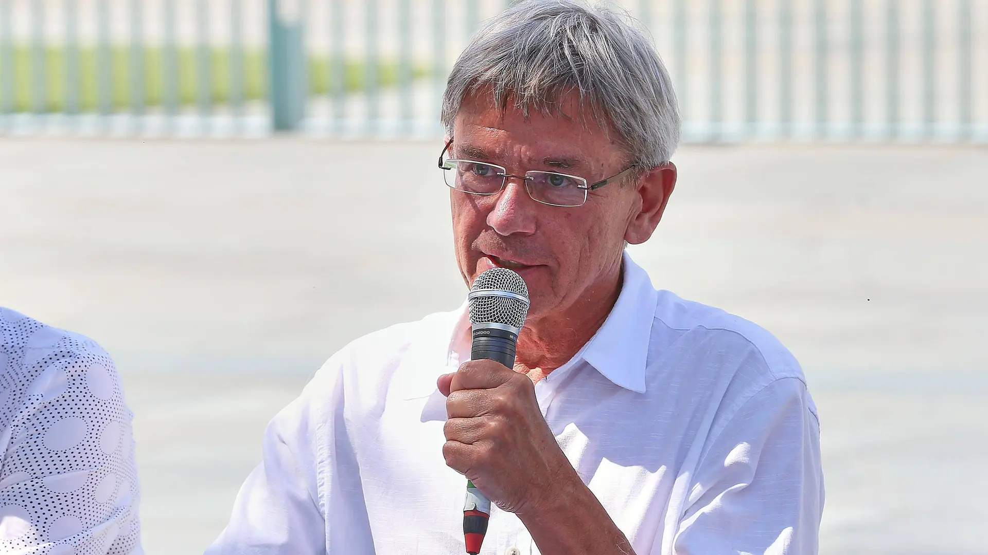 Mann mit grauen Haaren und Brille am Mikrofon