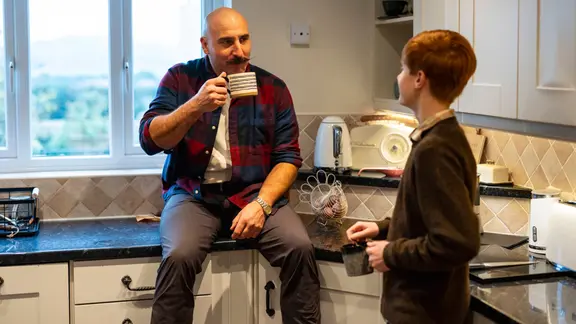 Vater und Sohn beim Kaffeetrinken in der Küche.