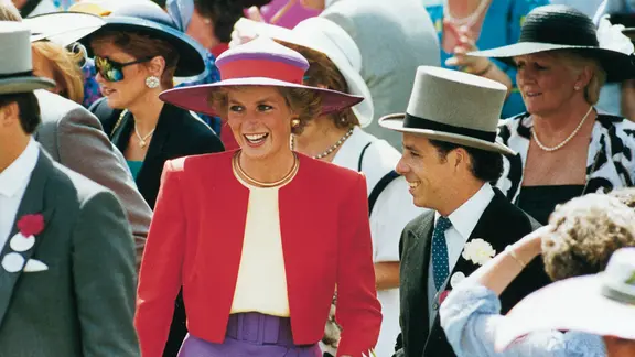 Doku "The Princess - Lady Diana": Lady Di, lächelnd, mit breitem Sommerhut in einer feinen Gesellschaft. 