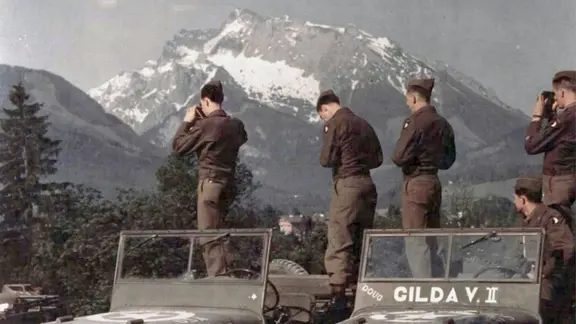 Amerikanische Soldaten auf zwei Jeep-Fahrzeugen vor Alpengipfeln.