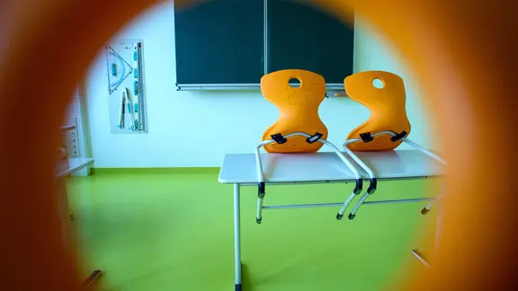 Stühle stehen in einem leeren Klassenzimmer auf einem Tisch.