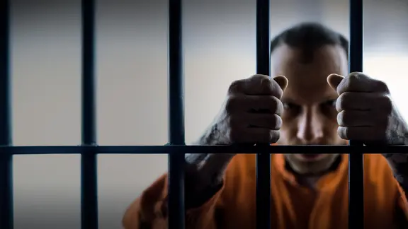 Ein Mann hinter Gittern.