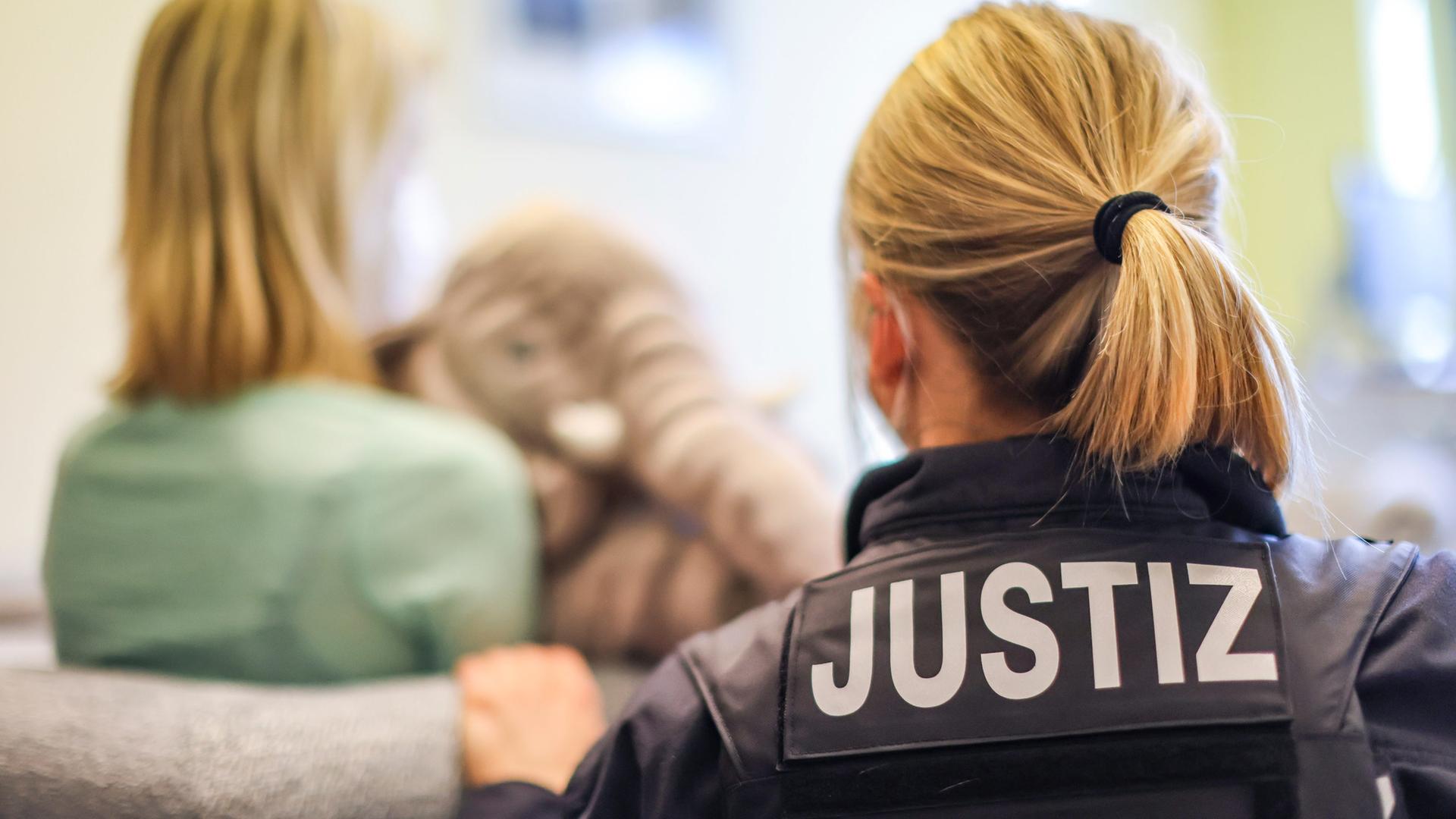 Eine Justizbeamtin und eine junge Frau zeigen ein einem Kinderschutzhaus exemplarisch eine Zeugenvernehmung, | picture alliance/dpa | Jan Woitas