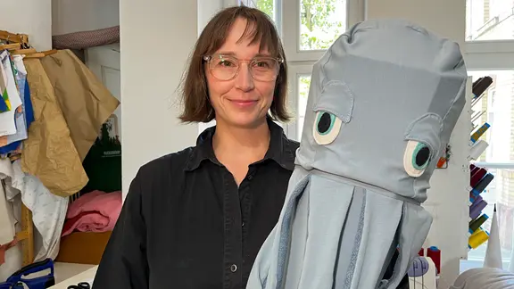 Eine Frau lächelt mit einer figürlichen Zuckertüte in die Kamera.