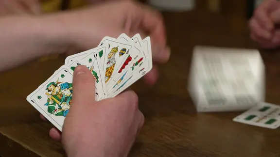 Hand hält ein Skatblatt