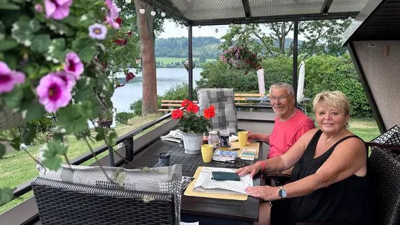 Marion und Andreas an einem Tisch ihrer Bungalow-Terrasse an der Talsperre Pirk