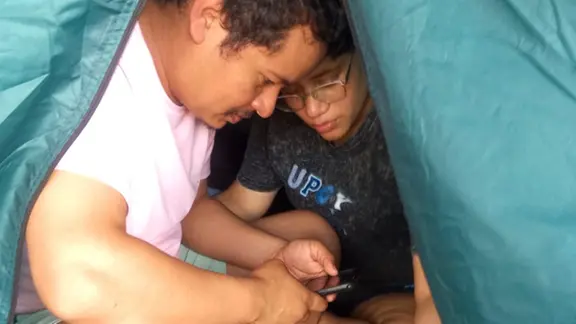 Erick Antonio Becerra Afanador (li.) und Ehefrau Erika Yelisa Quijada Brelio sitzen eng zusammen in einem Zelt in Venezuela.