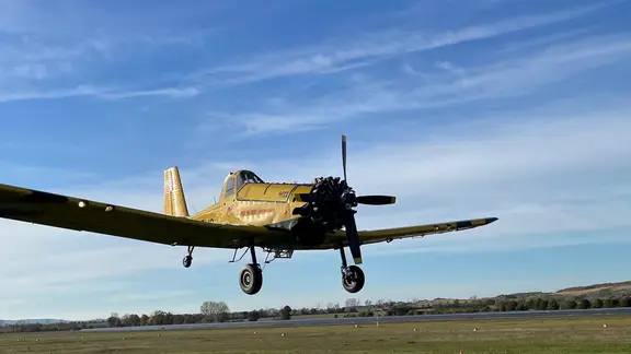 Ein Flugzeug fliegt knapp über dem Boden.