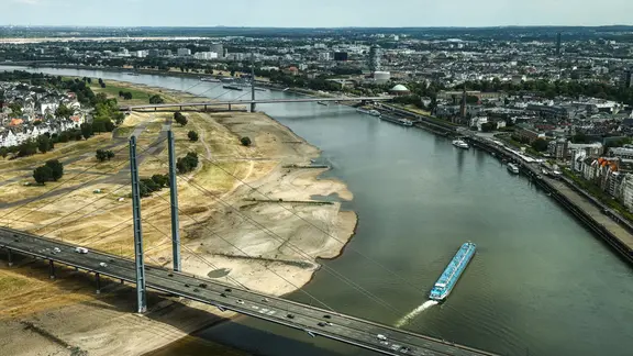 Ein Binnenschiff fährt mit geringer Ladung bei Niedrigwasser am Rheinknie in der nordrhein-westfälischen Landeshauptstadt vorbei.