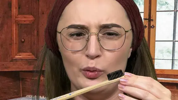 Frau schaut auf Zahnbuerste