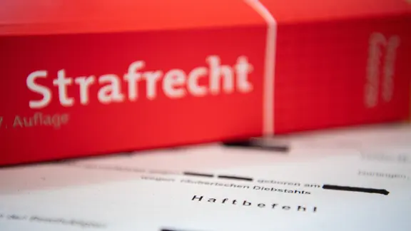 Eine Abschrift eines Haftbefehls des Amtsgerichts Nürtingen liegt mit einem Strafrecht - Buch auf dem Tisch.