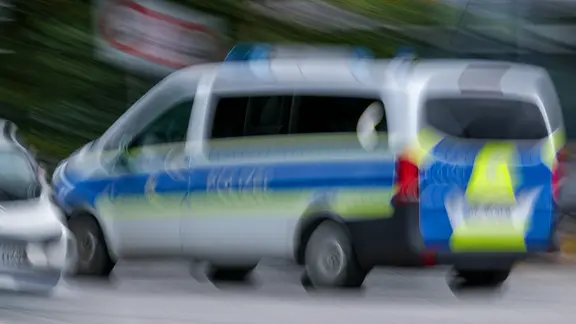 Ein Polizeiauto fährt mit Blaulicht auf Einsatzfahrt. Das Foto ist verschwommen.