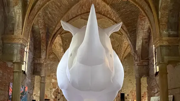 Ein großes, luftgefülltes, weißes Nashorn steht in einer Kirche.