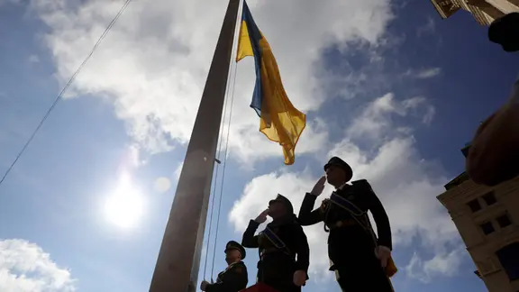 Soldaten grüßen die ukrainische Flagge.