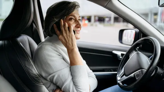 Frau sitzt im Auto und telefoniert