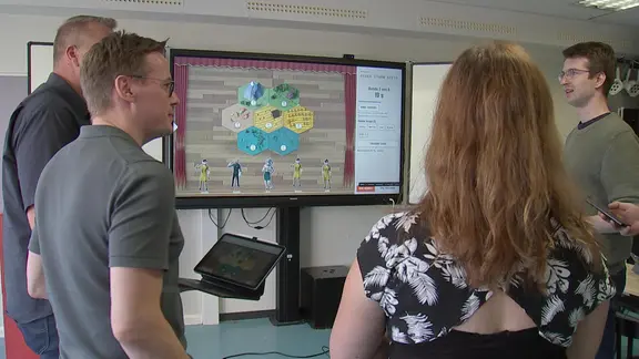 Menschen stehen um einen Monitor herum.