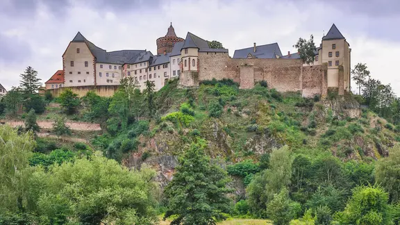 Burg auf einem Berg über dem Fluss im Sommer