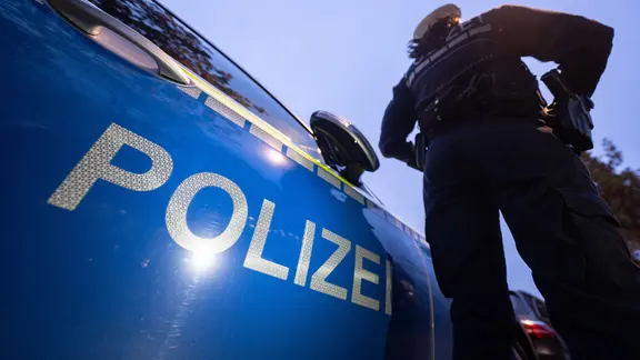 Polizist neben einem Polizeiauto
